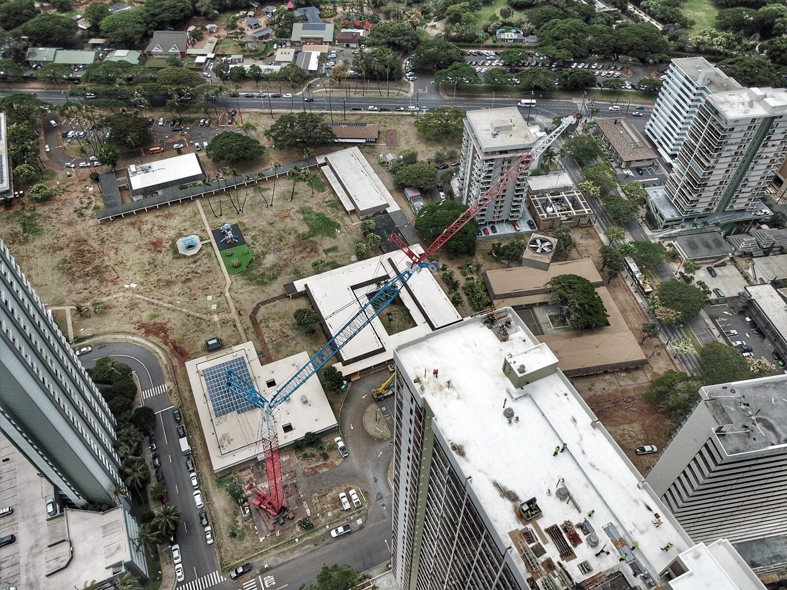 An elevated view of crane operations between city buildings